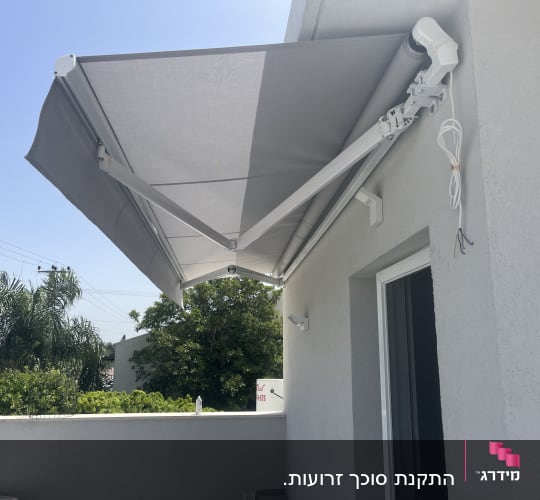 סוכך אפור מותקן על קיר חיצוני של מבנה.